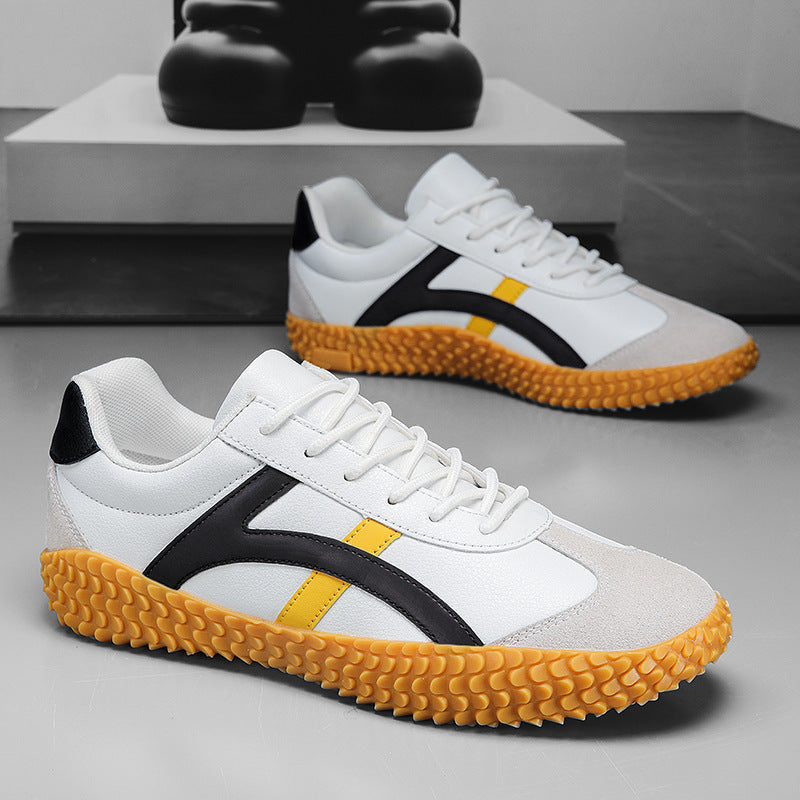 White sneakers with black and yellow accents on a gray surface