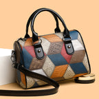 Multicolored patchwork handbag with black handles and strap on a beige background