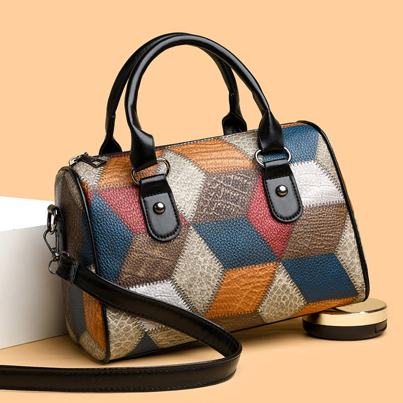 Multicolored patchwork handbag with black handles and strap on a beige background