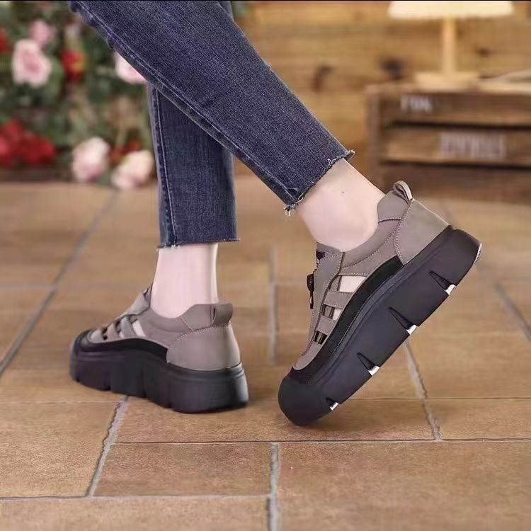 Gray sandals with black soles worn on a tiled floor.