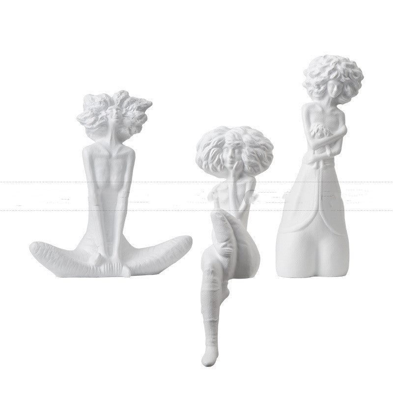 Three white ceramic wall hooks shaped like women with different hairstyles on a white background