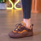 Brown and orange sneaker worn with jeans on a blurred background