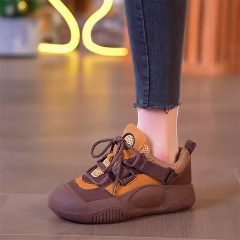 Brown and orange sneaker worn with jeans on a blurred background