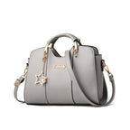 Gray handbag with star-shaped charm and gold accents on a white background