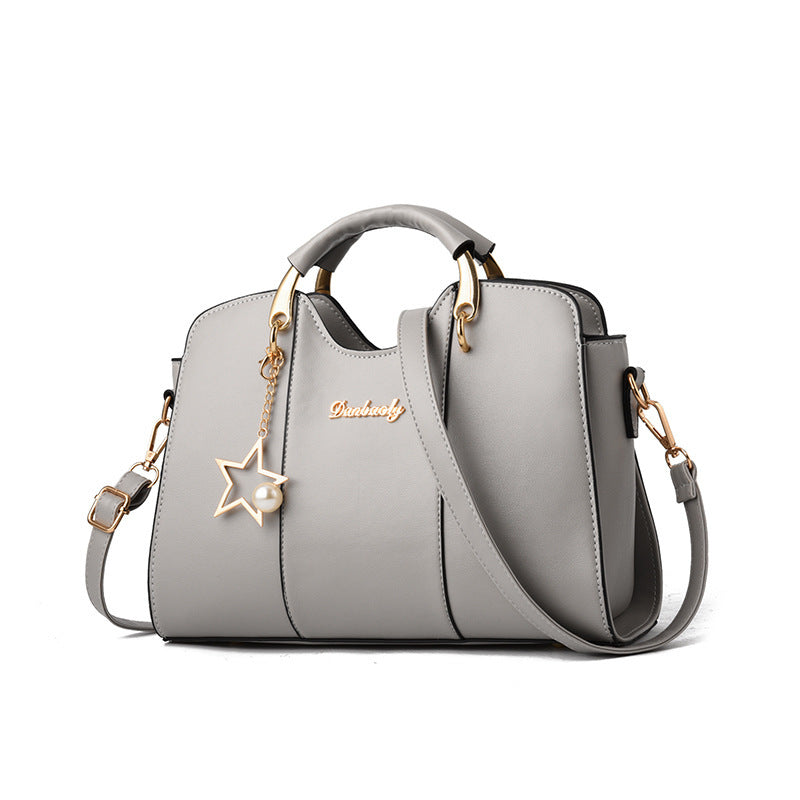Gray handbag with star-shaped charm and gold accents on a white background
