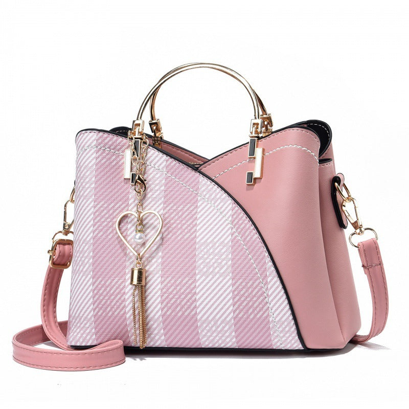 Pink handbag with a heart-shaped keychain on a white background