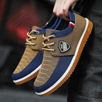Brown and blue sneakers with a brand logo held by a person against a dark background