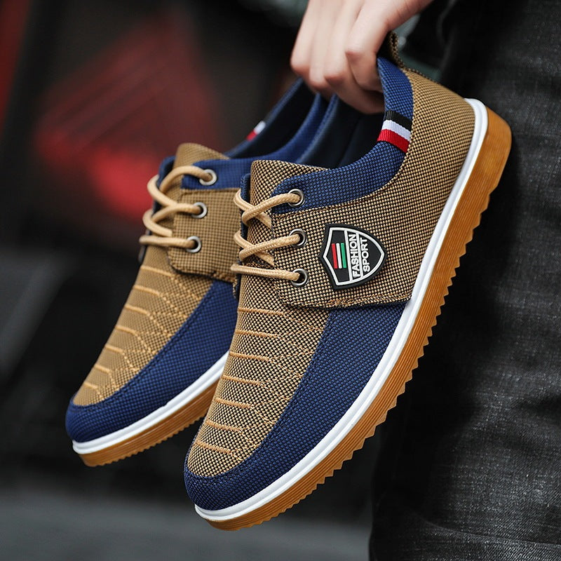 Brown and blue sneakers with a brand logo held by a person against a dark background