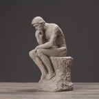 Stone sculpture of a thinker on a wooden surface with a dark background