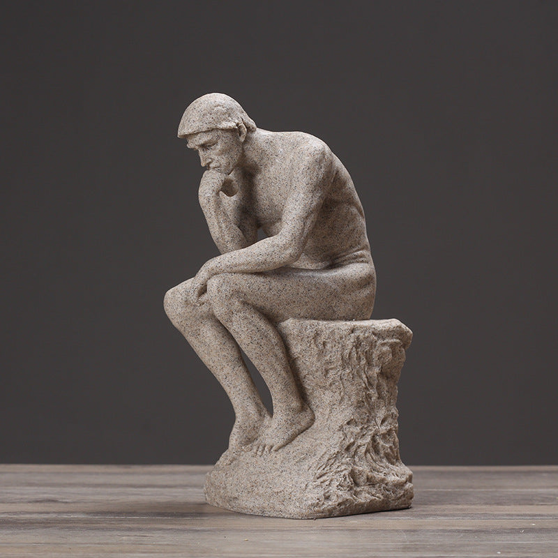 Stone sculpture of a thinker on a wooden surface with a dark background
