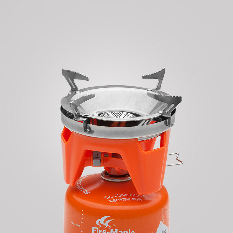 Portable gas stove with orange body and silver top on a light gray background