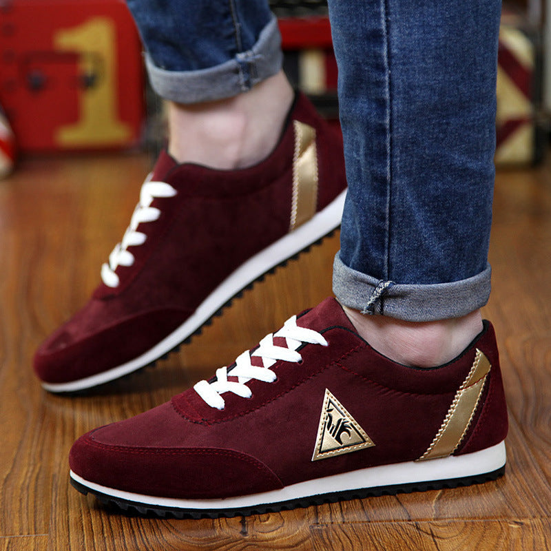 Burgundy sneakers with white laces worn by a person on a wooden floor.