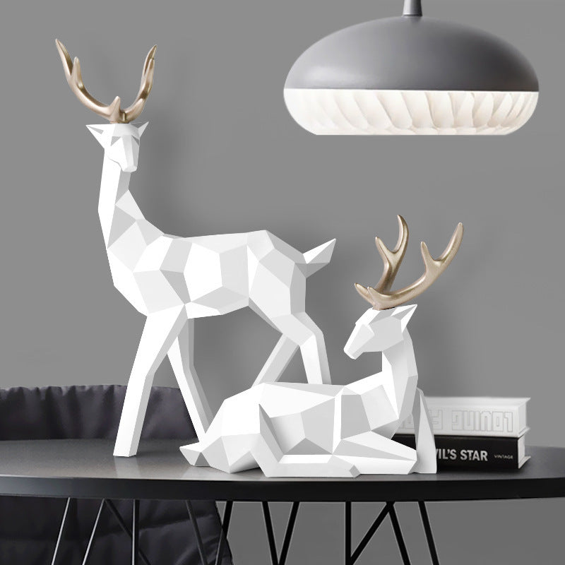 Geometric deer sculptures on a table with a modern lamp in the background