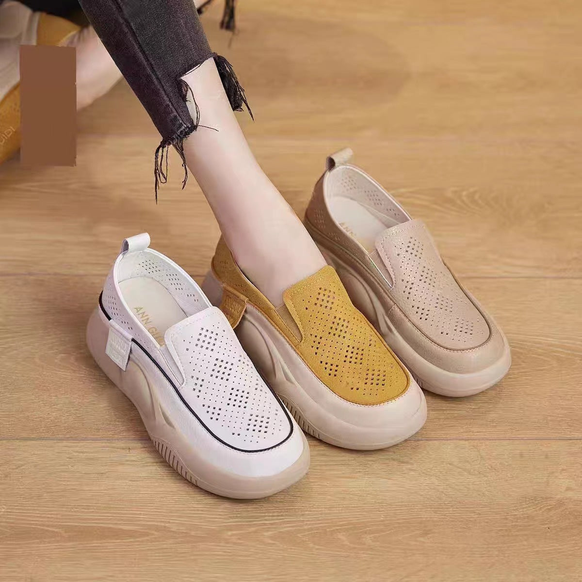 Loafer shoes with beige and yellow accents on a wooden floor.