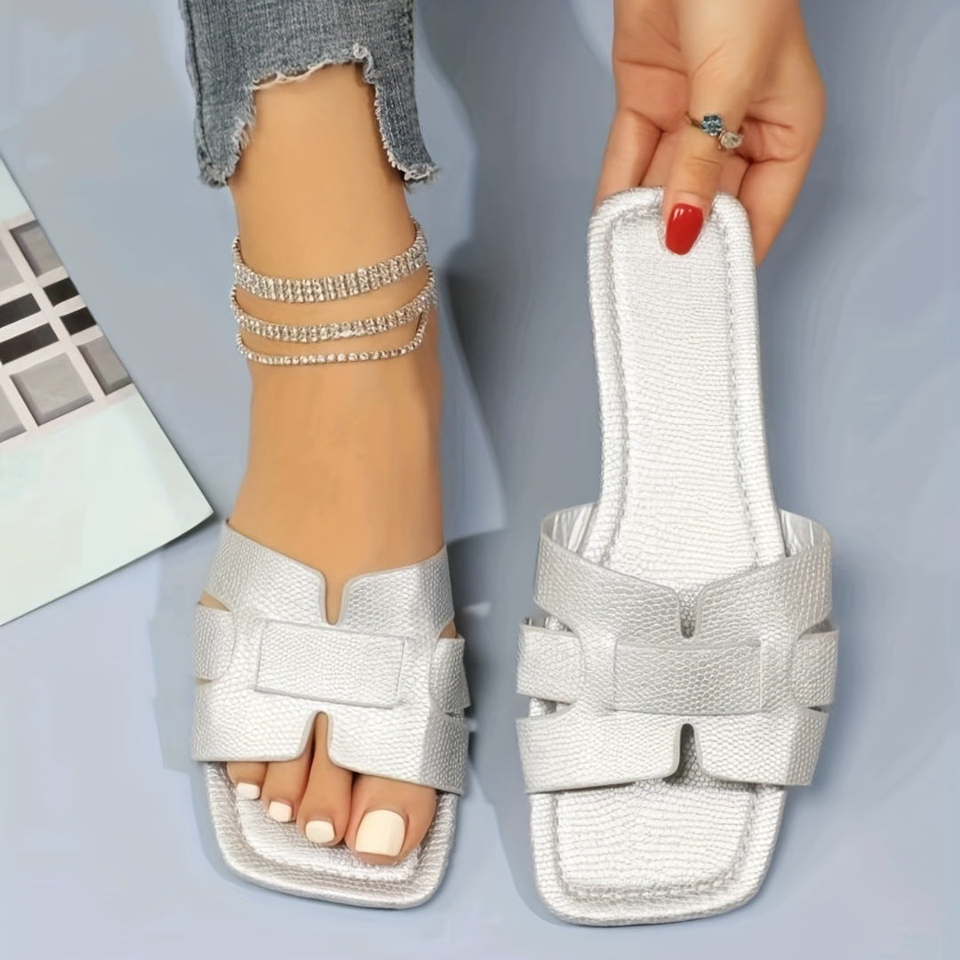 Silver sandals being worn with a neutral background