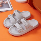White sandals with two straps on an orange surface
