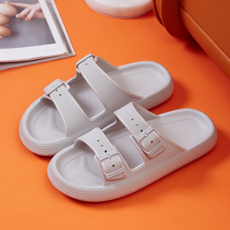 White sandals with two straps on an orange surface