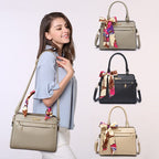 Woman holding a beige handbag with colorful accents, surrounded by other handbags on a light gray background.