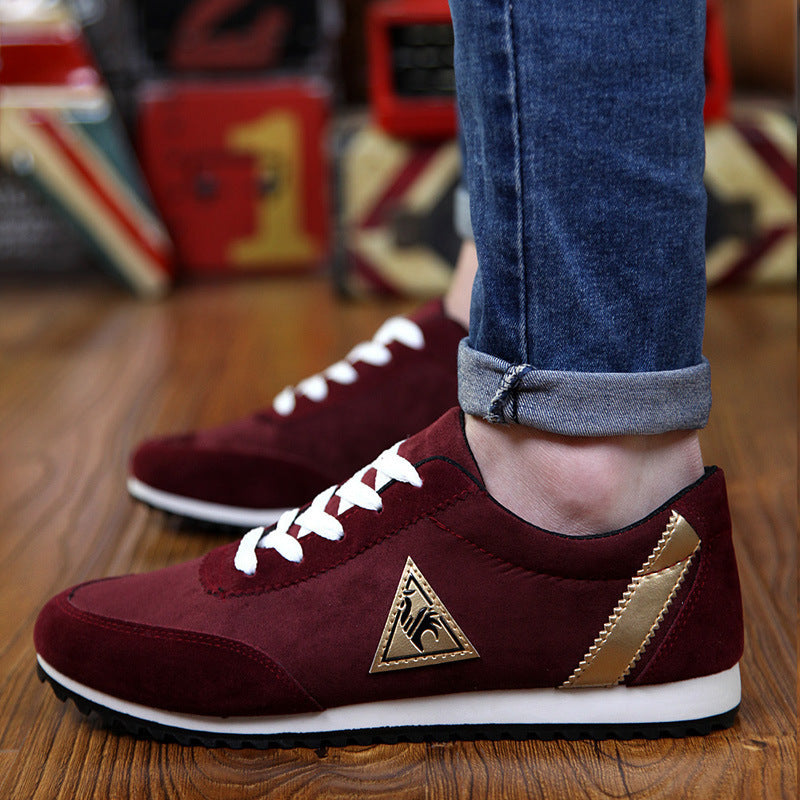 Maroon sneakers with a gold logo worn by a person on a wooden floor.