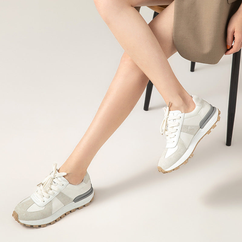 Person wearing white sneakers with gray accents on a light background