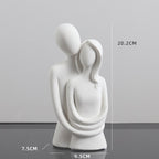 White abstract sculpture of two figures embracing with measurements on a gray background