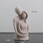 Abstract sculpture of two figures embracing with dimensions indicated on a gray background