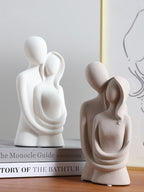Two white abstract sculptures on books with a blurred background