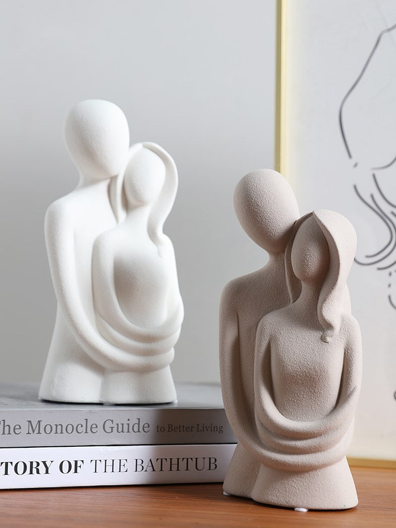 Two white abstract sculptures on books with a blurred background