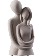 Statue of two abstract figures embracing on a white background