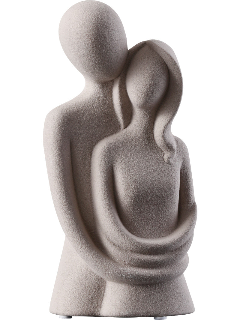 Statue of two abstract figures embracing on a white background