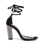 Black high-heeled shoe with clear transparent sole and rhinestone heel on a white background