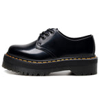 Black leather shoe with yellow stitching on a white background