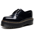 Black leather shoe with yellow stitching on a white background
