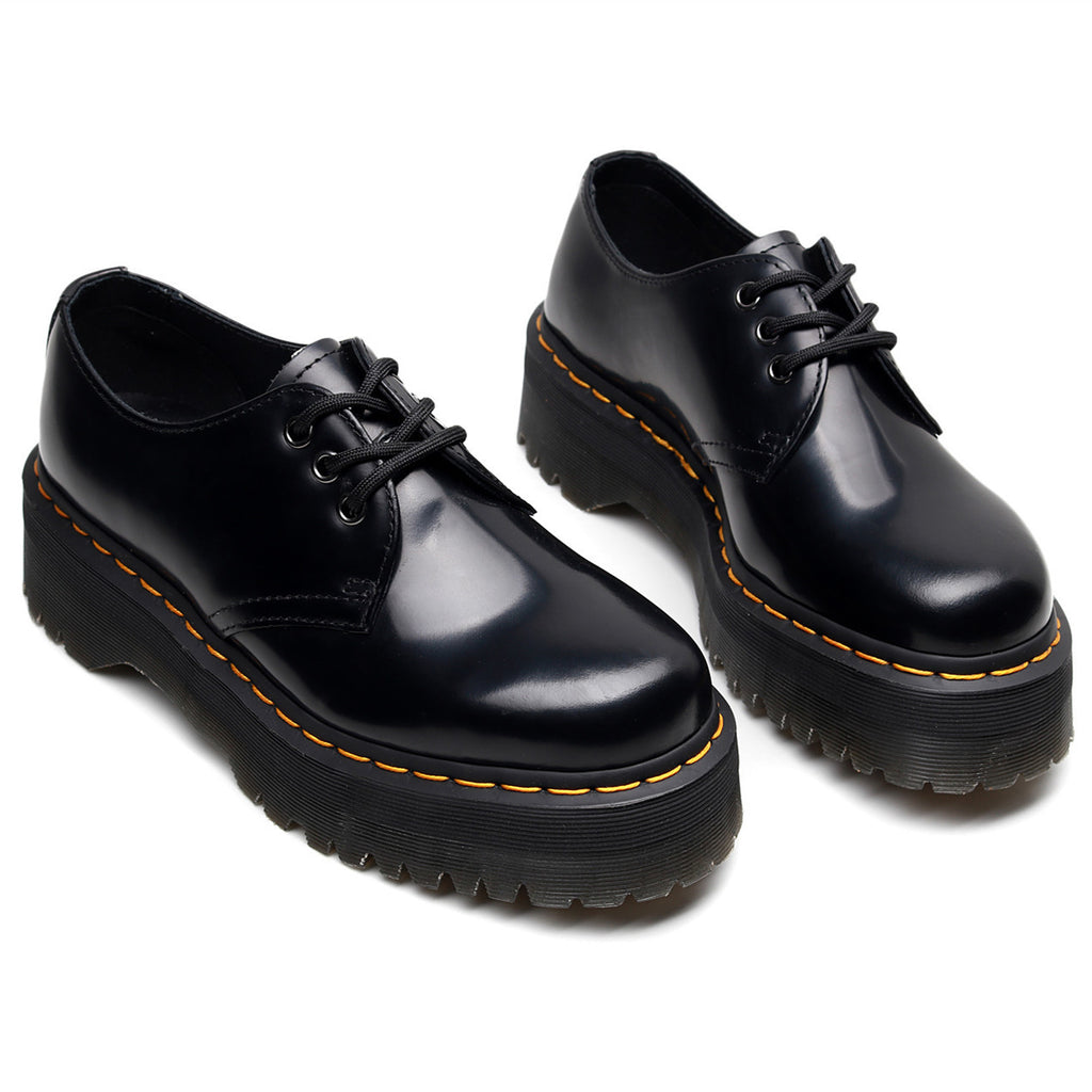 Pair of black leather shoes with orange stitching on a white background