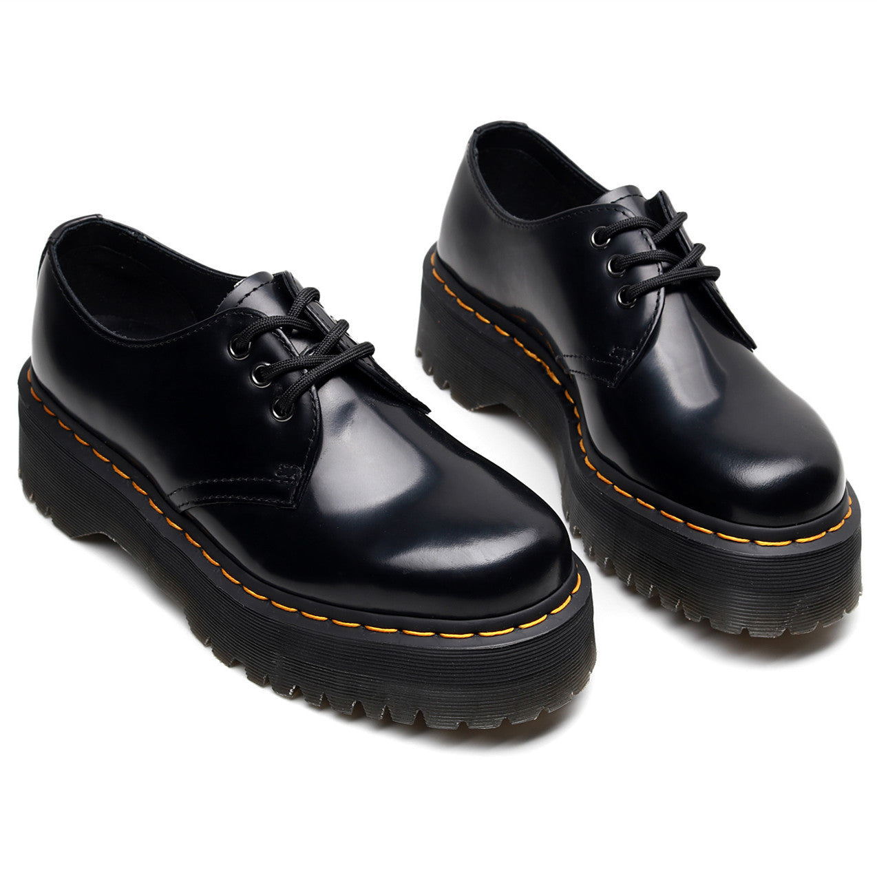 Pair of black leather shoes with orange stitching on a white background
