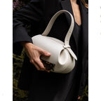 Person holding a white handbag with a dark background