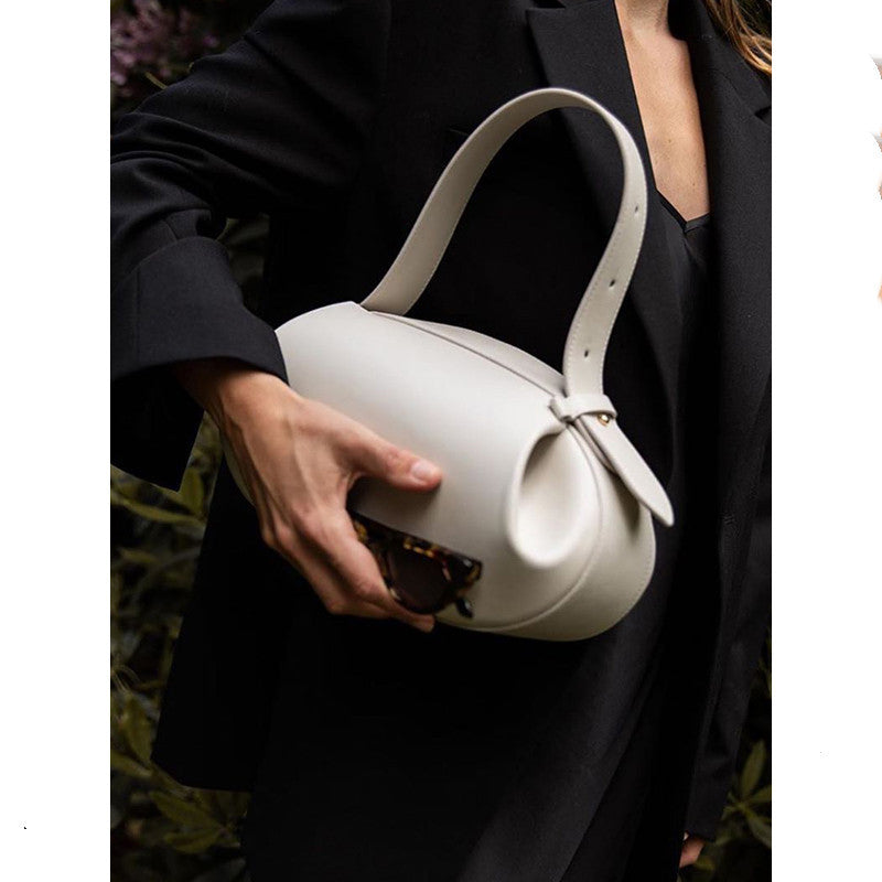 Person holding a white handbag with a dark background
