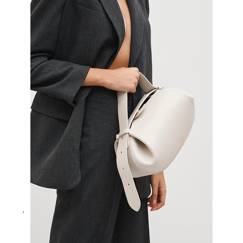 Person holding a white handbag against a plain background