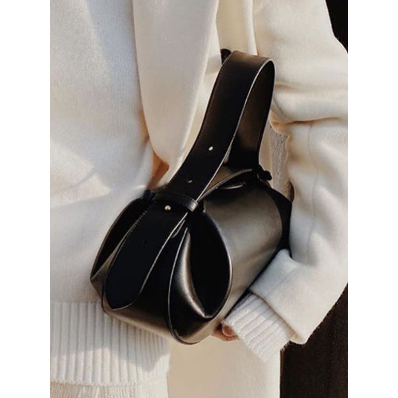Black leather handbag held by a person wearing a white sweater