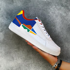Colorful sneaker with a white sole held against a gray background
