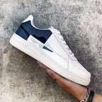 White sneaker with navy accents held against a textured gray background