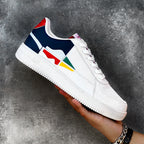 White sneaker with colorful design held by a hand against a gray background
