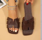 Brown sandal with adjustable straps held by a hand on a beige background