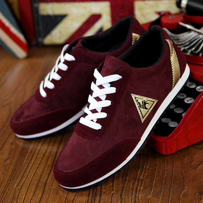 Maroon sneakers with white laces on a wooden surface, with a red and black object in the background.