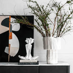 Decorative setup with a vase, sculpture, and abstract painting on a shelf.