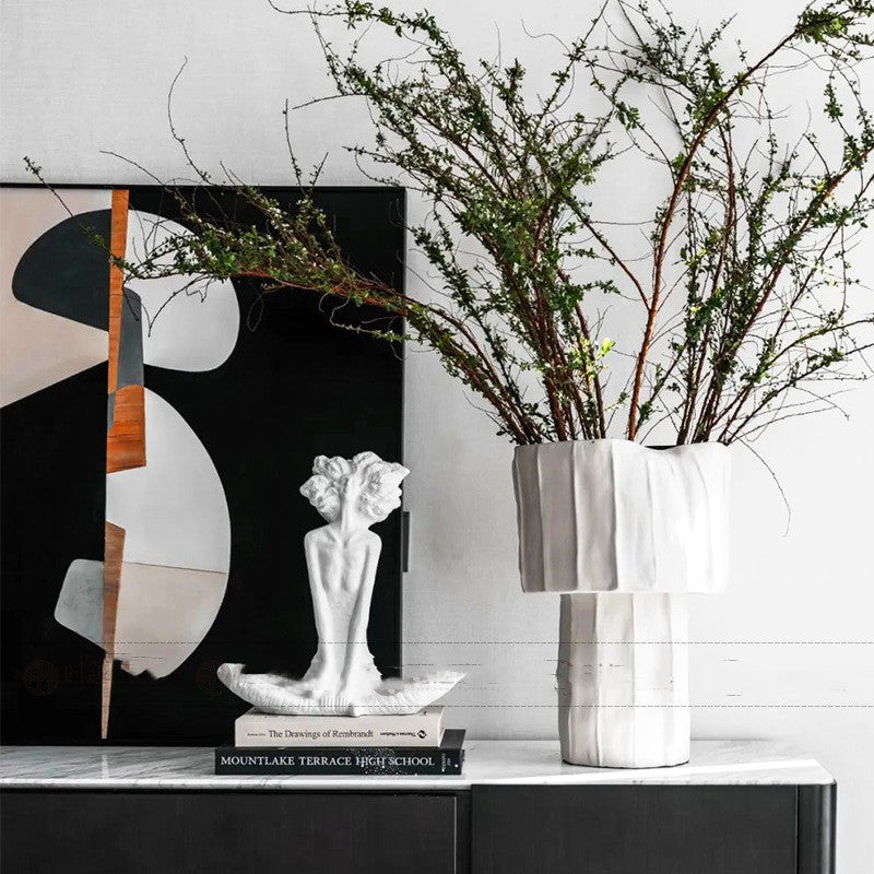 Decorative setup with a vase, sculpture, and abstract painting on a shelf.