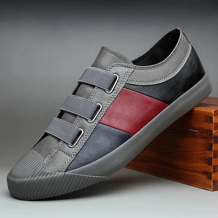 Gray and red sneaker with velcro straps on a gray background