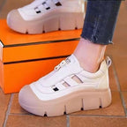 White and beige sneakers worn with orange box in the background