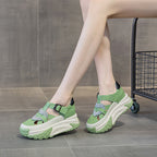 Green and white sandals worn by a person on a wooden floor.