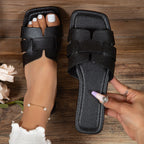 Black sandals worn on feet with a wooden background